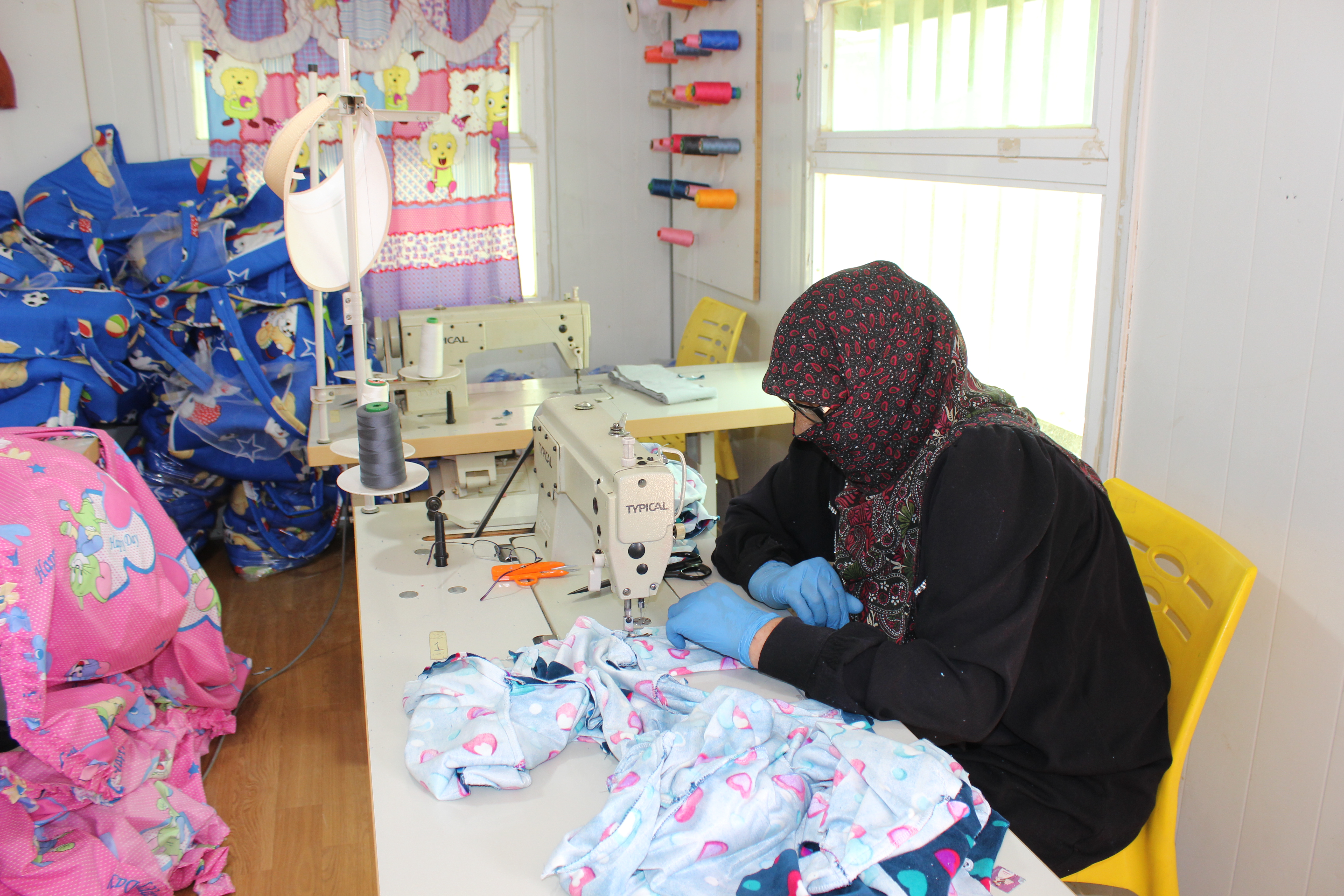 Nawal Saed Mohammed, 60, sewing baby outfits as master cutter at the UN Women Oasis centre in the Za’atari refugee camp. Photo: UN Women/Ye Ji Lee