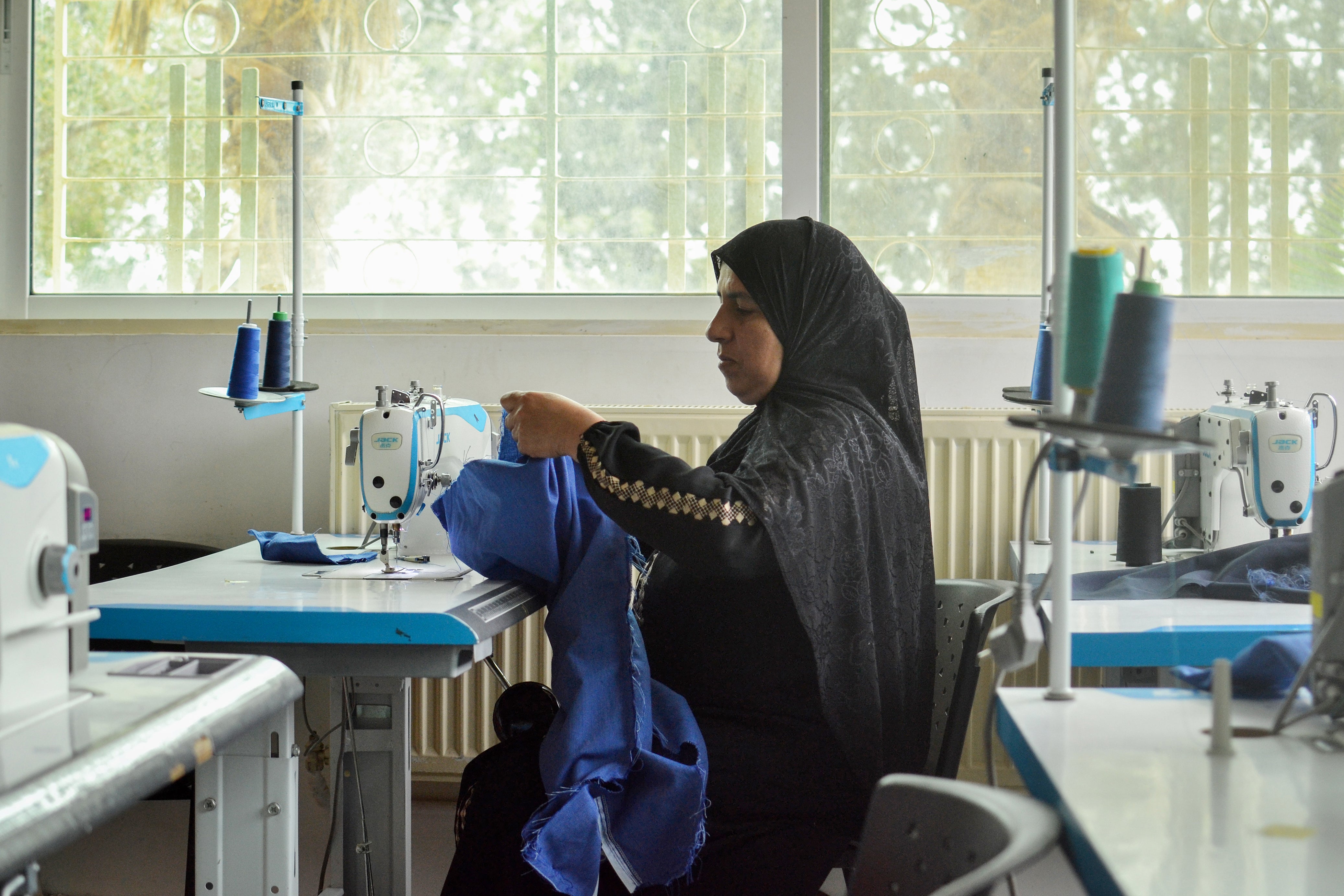 Taghreed Al-Issa works on school uniforms at the UN Women Al-Muwaqqar Oasis Centre. Photo: UN Women/Bashar Al-Jabari