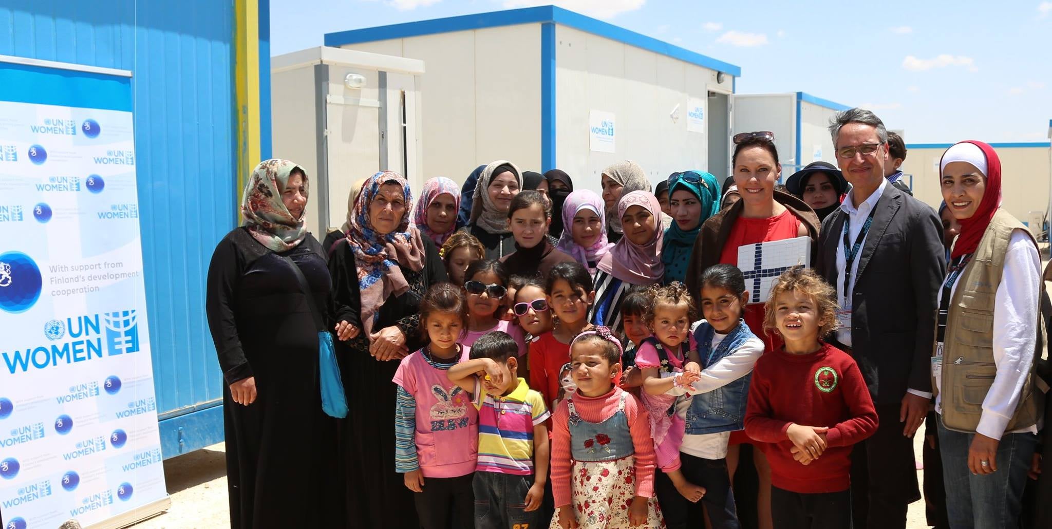 Finland Minister for Foreign trade and Development, Anne-Mari Virolainen received a handcrafted mosaic from the women within the UN Women Oasis and joined the UN Women Country Representative Ziad Shiekh, women and children of the Oasis for a group photo. Photo source: UN Women/ Ghaith Al Bahri