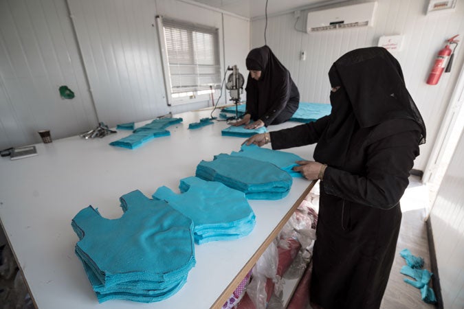 Syrian women cutting fabrics to produce cloths for a tailoring workshop. (UN Women/Christopher Herwig)